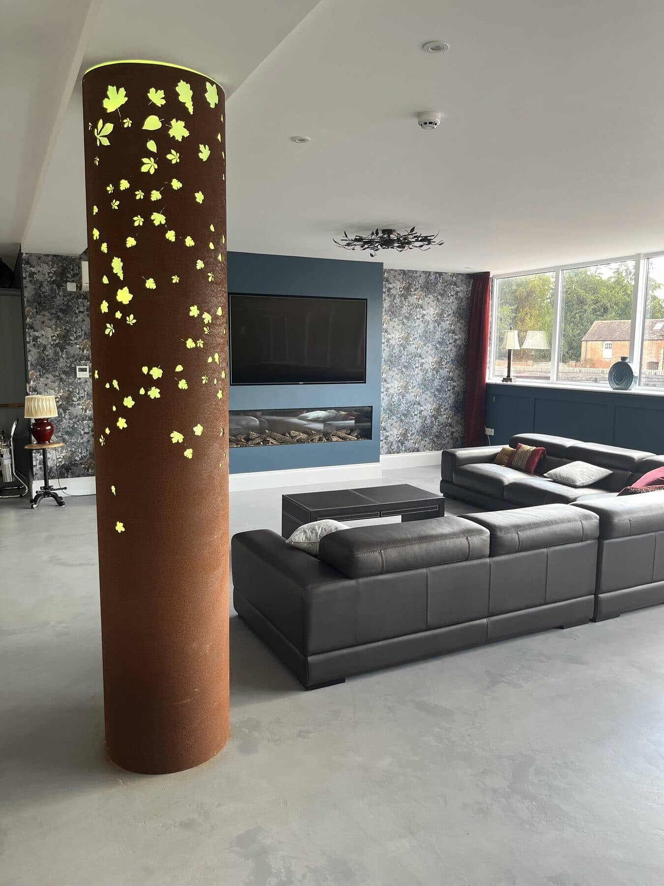 Open plan living room with a backlit perforated feature column, a linear fire and downlights set into the ceiling