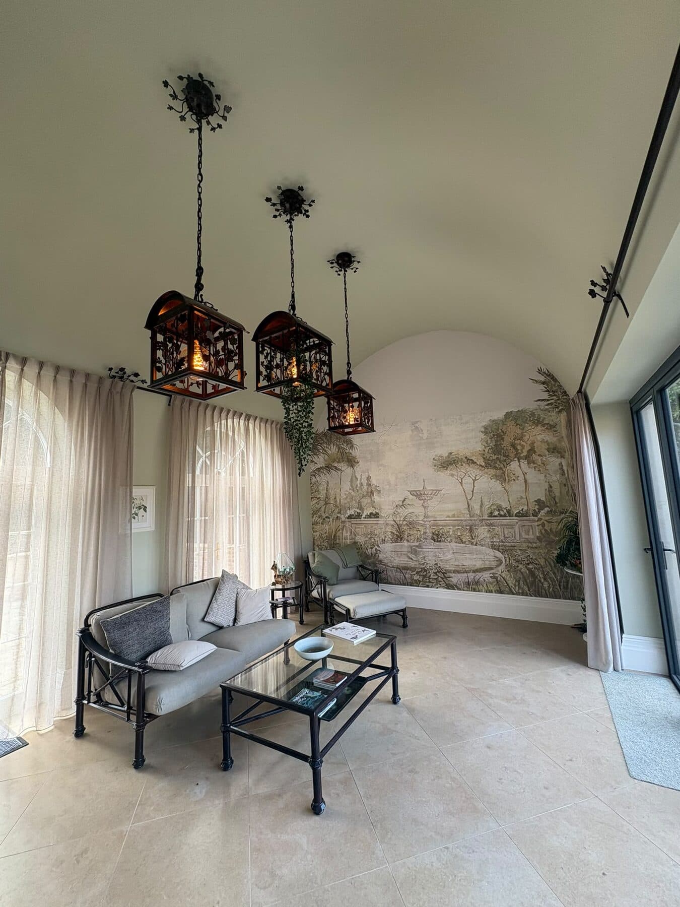 Garden room with a vaulted ceiling and three hanging lantern pendants above a seating area