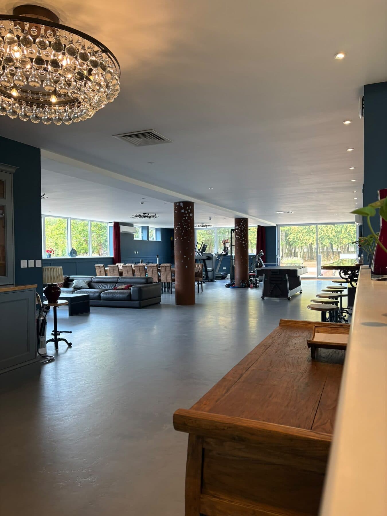 Large leisure suite with a statement glass chandelier, ceiling downlights and lighting run through the seating and gym areas